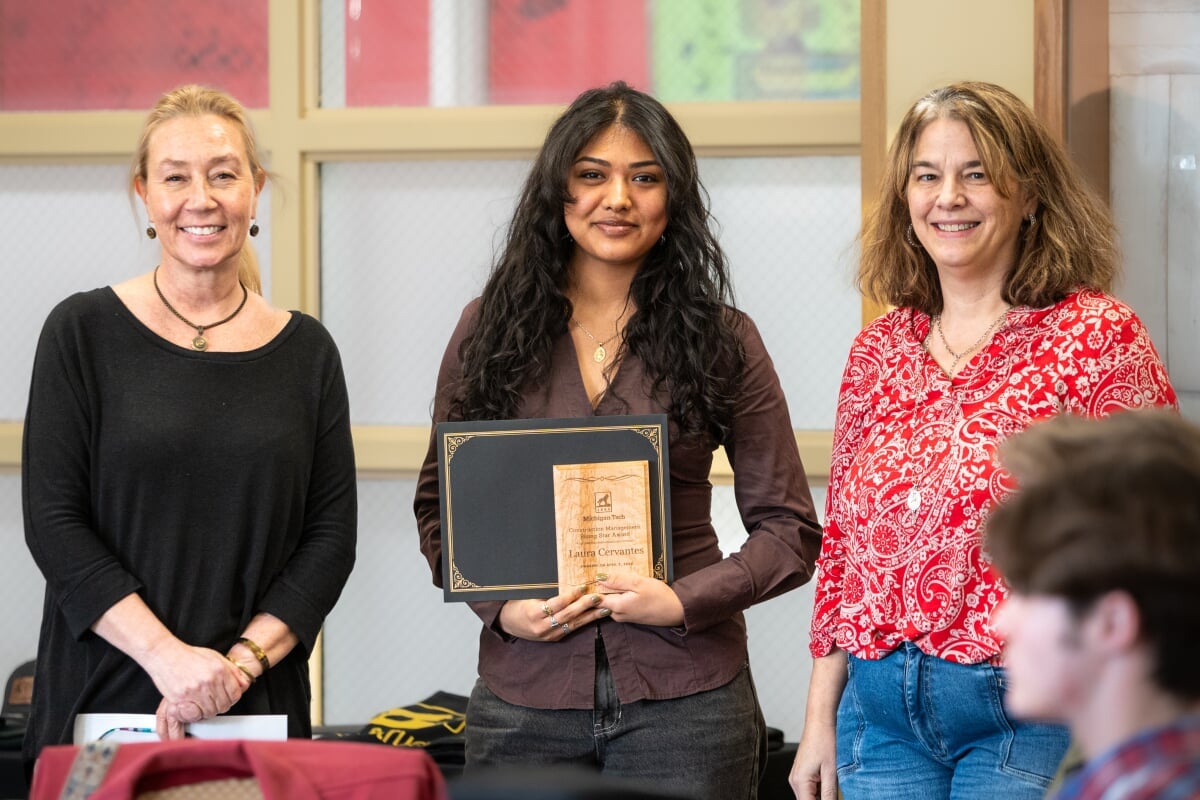 A student holding their award with two faculty members. From left to right - Kerri Sleeman, Laura Cervantes, Jen Miller