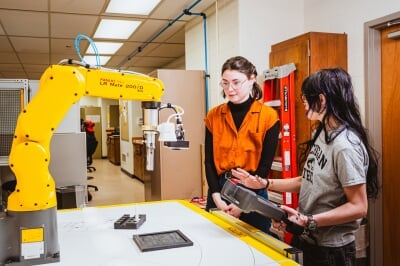two students working with a robotic arm