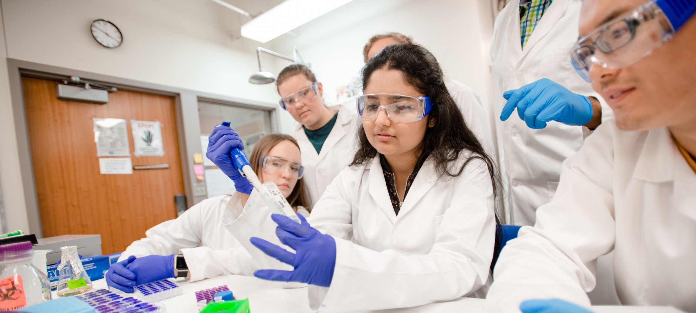 Biochemistry students working with their instructor in a research lab.