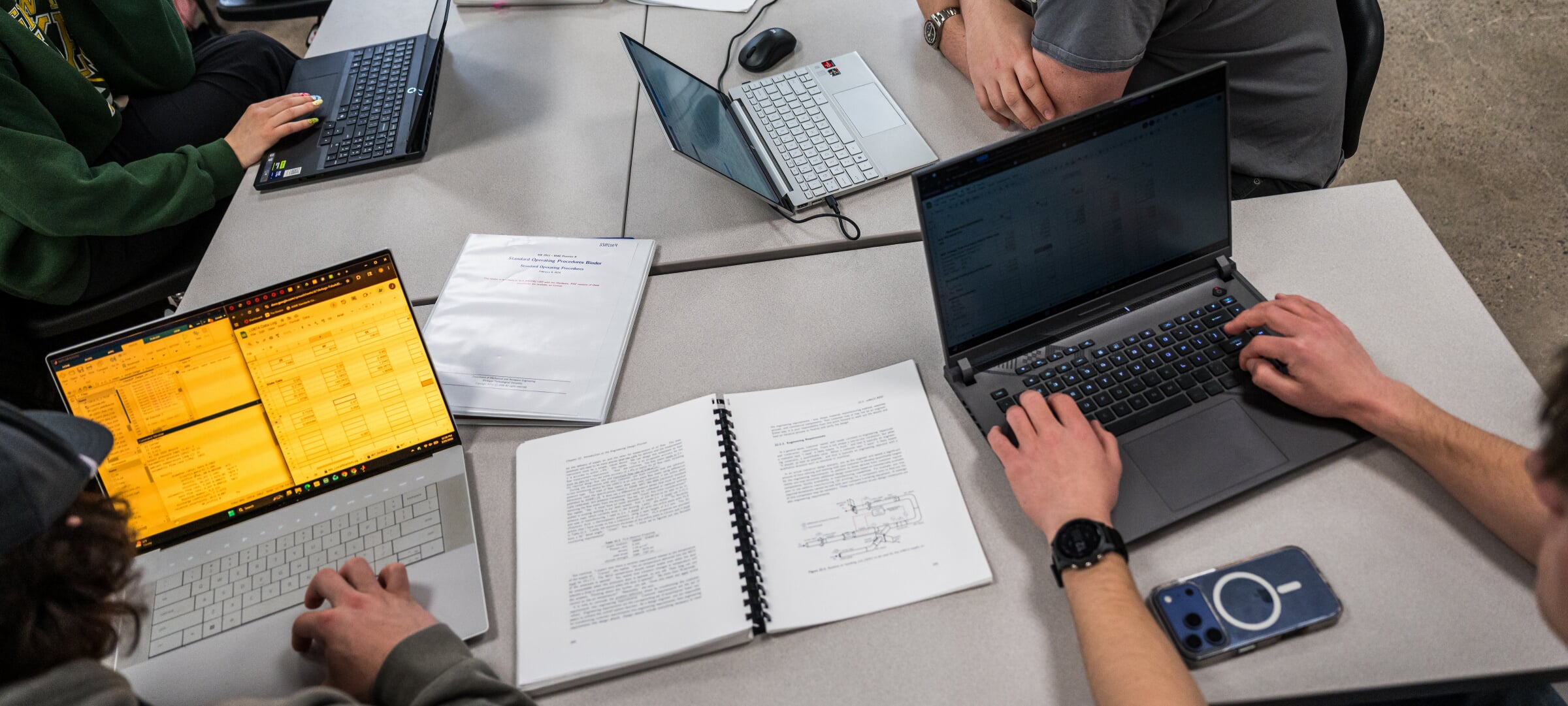 Engineering students working on laptops and engineering problems.