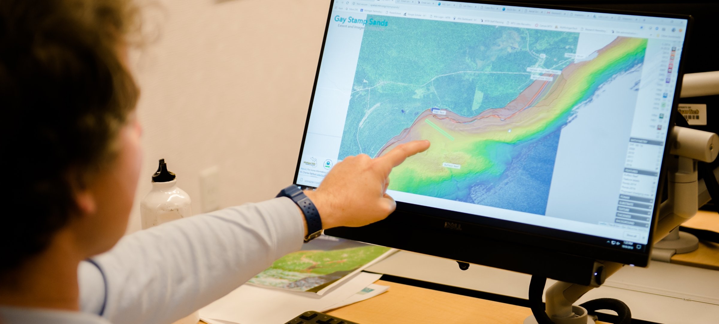 Undergraduate student pointing to a computer screen with a data map.