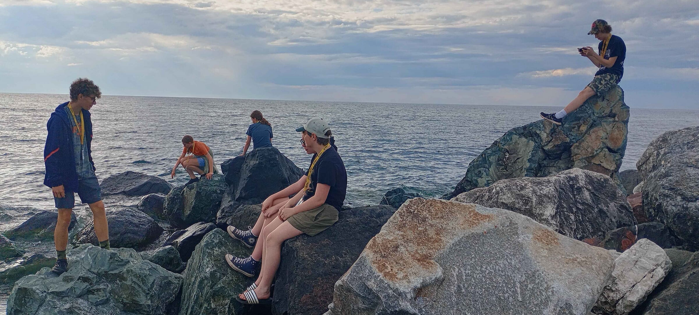 Geological engineering students sitting on rocks off Lake Superior.