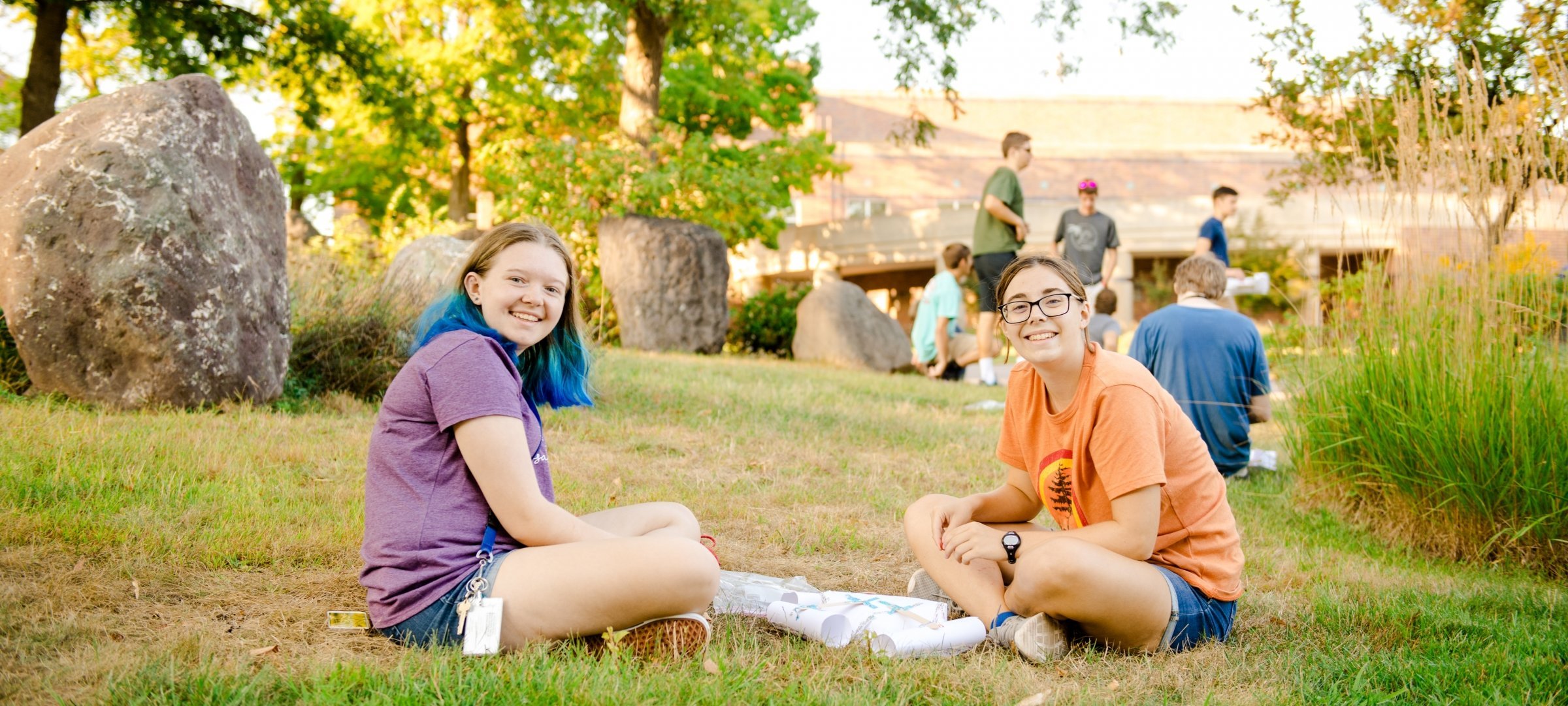 Students sitting down on the lawn and talking during during orientation.