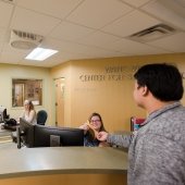Student meeting with the registrar handing in a paper when checking in. 