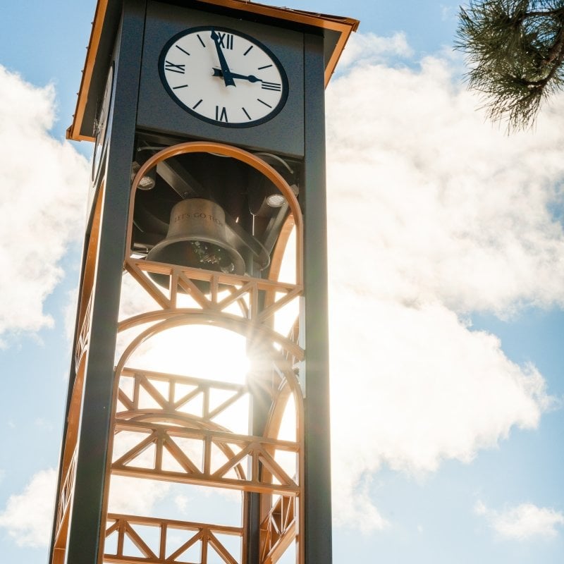 Campus clock tower with the sun behind it.
