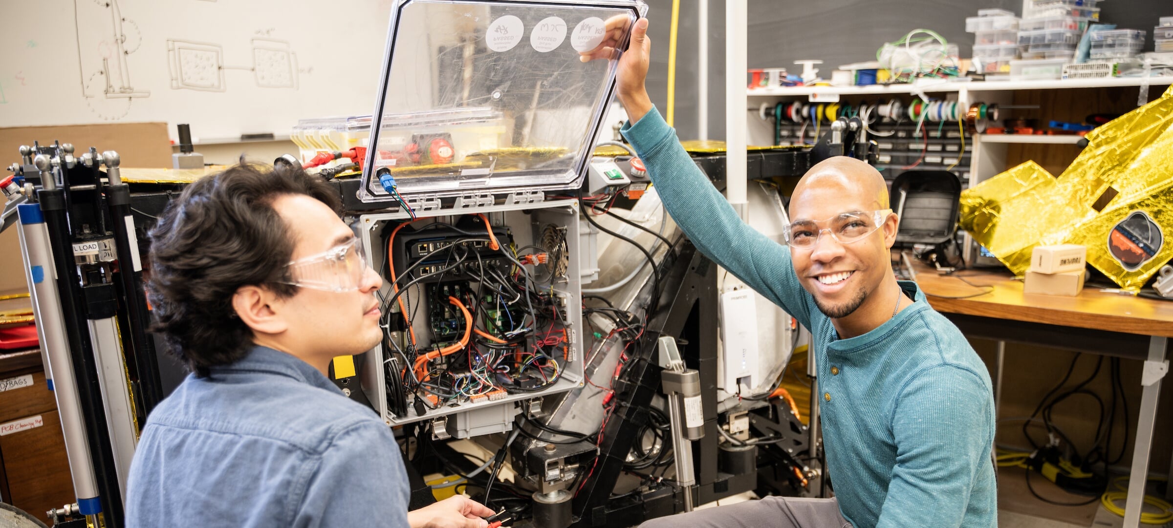 Two people working on a piece of electrical equipment for the Aerospace Enterprise team