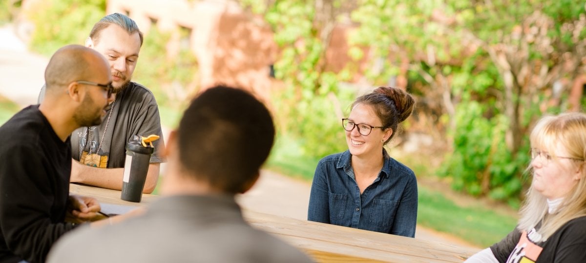 Students talking around a table outdoors.