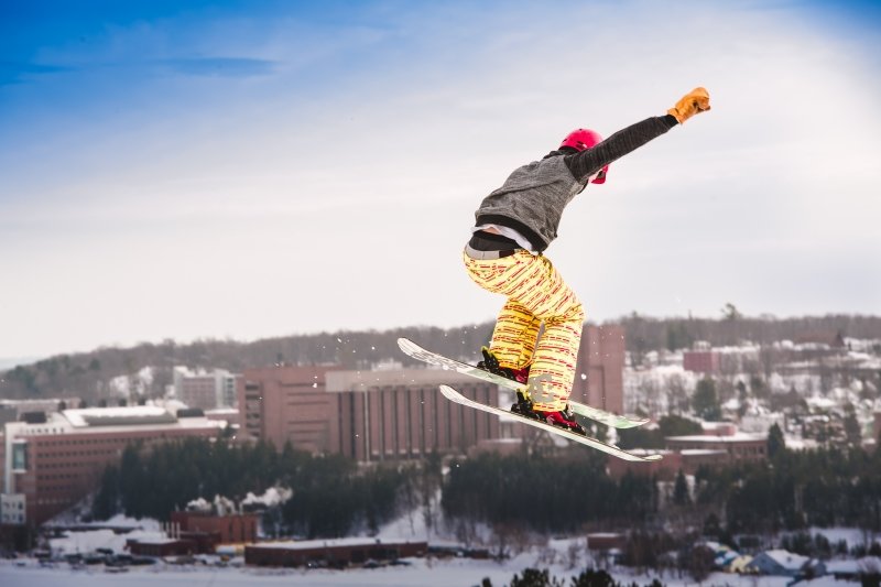 a skiier taking a jump with Michigan Tech in the background