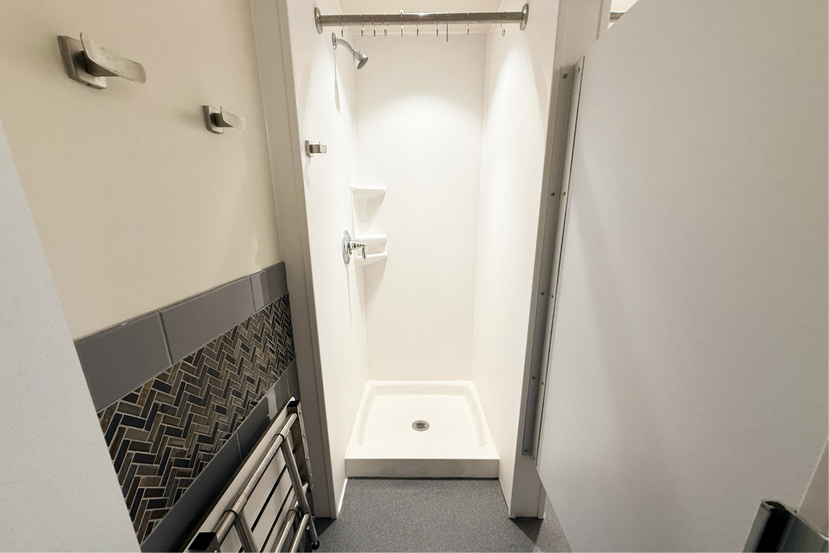 A shower stall with hooks and a bench.