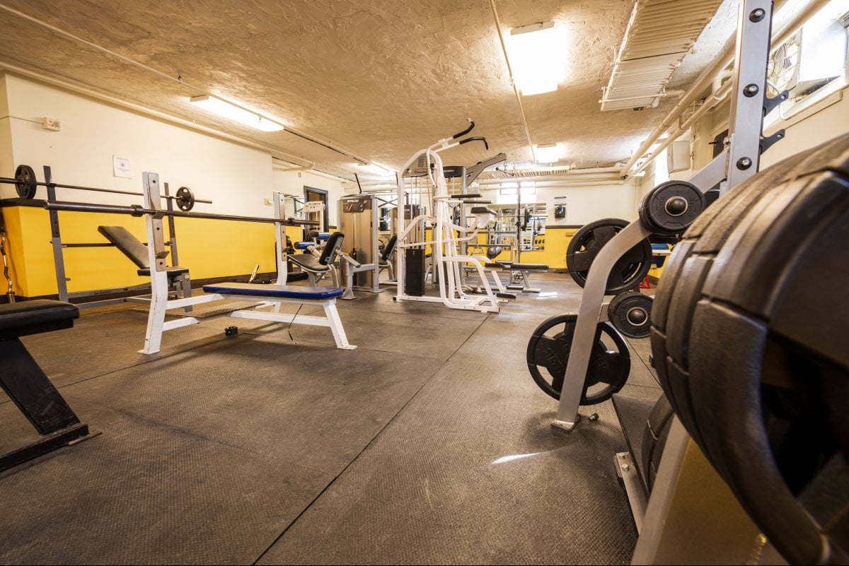 fitness equiptment including bench presses and free weights inside the Doulgas Houghton Hall fitness center