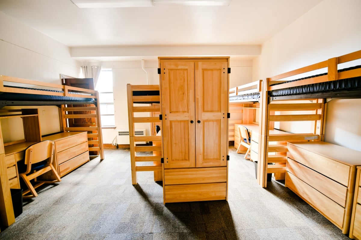 Three loft beds with desks below and a wardrobe in the middle.