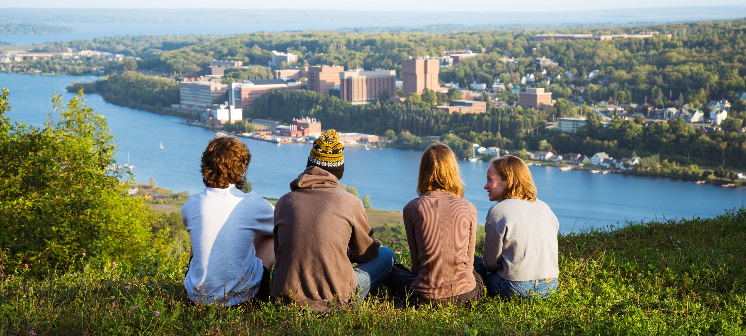 Students sitting on the top of Mt Ripley overlooking Portage Canal and MTU campus.