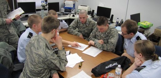 A group of Air Force ROTC and Army ROTC students sitting around a table collaborating on a project