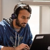 A man wearing headphones works on a laptop.