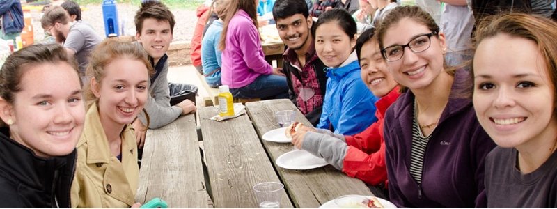 A group of students sit at a picnic table. 