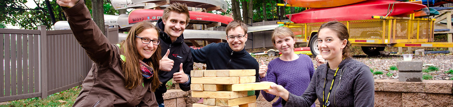Students smile while playing a game of oversized Jenga.