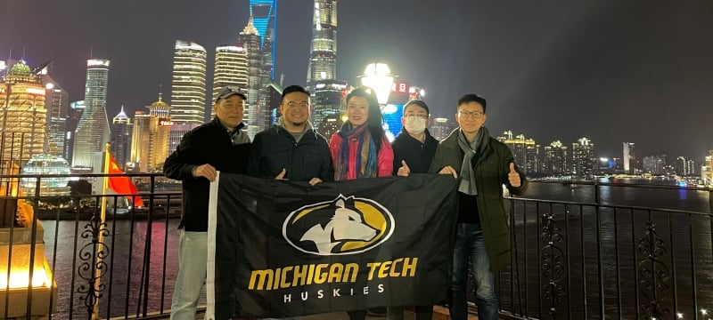 Five alumni holding MTU flag in China