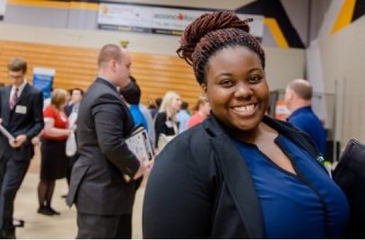 A female student in a business suit smiles during Career Fair.