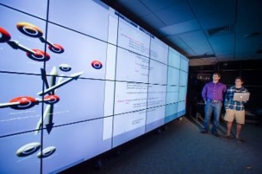 Two students review a model projected on a classroom wall.