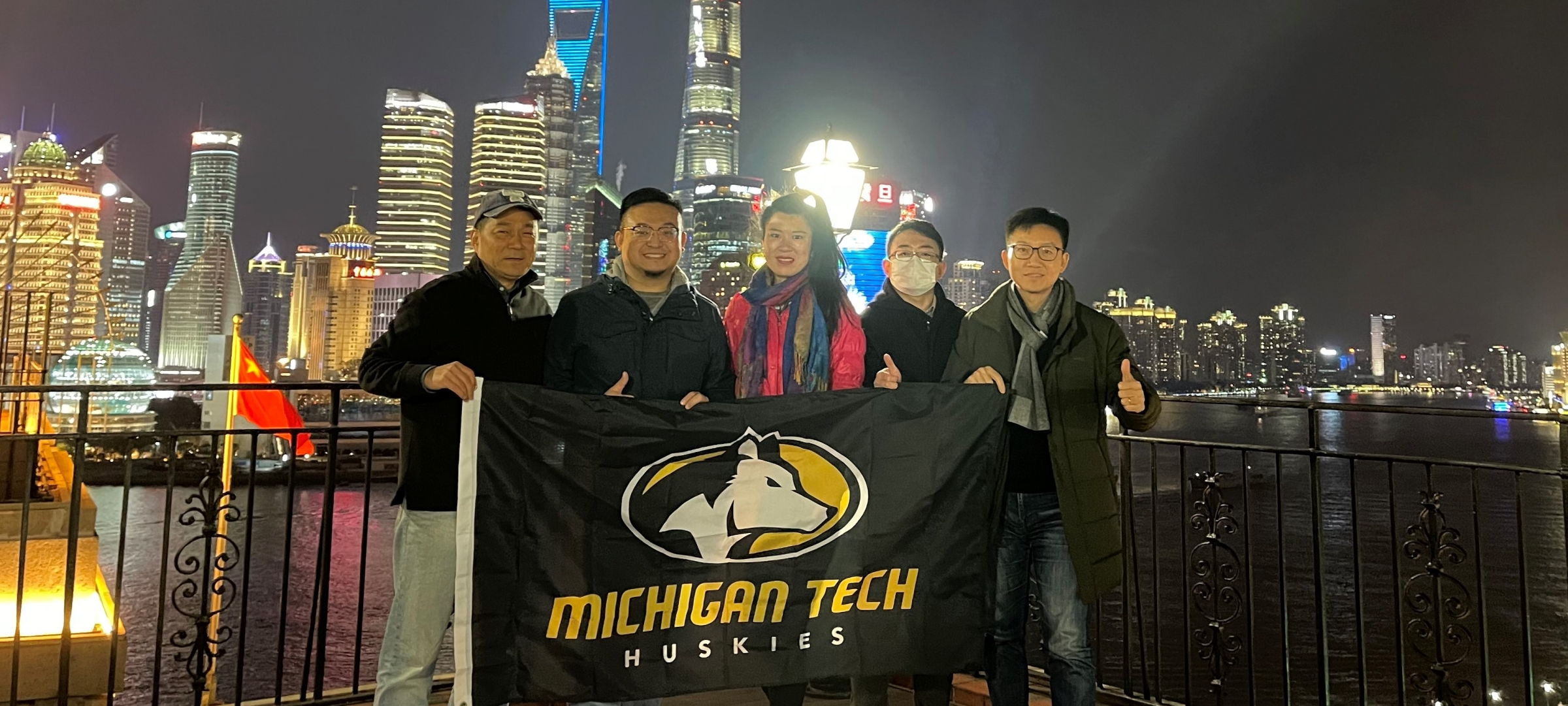 Michigan Tech alumni holding an MTU Husky banner in China.