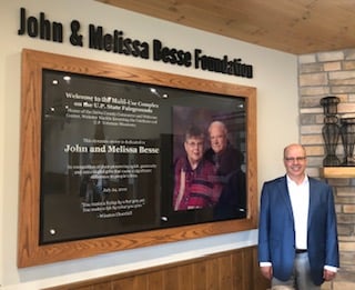 Greg Besse stands in front of commemorative display case for John and Melissa Besse Foundation