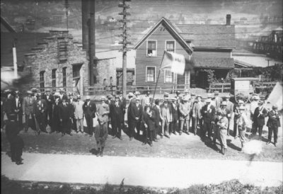 From 1911, men standing in downtown Houghton with one holding a flag
