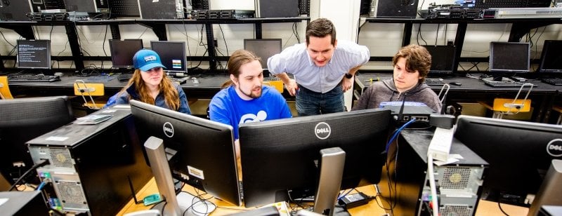 Students and faculty looking at a bank of computers