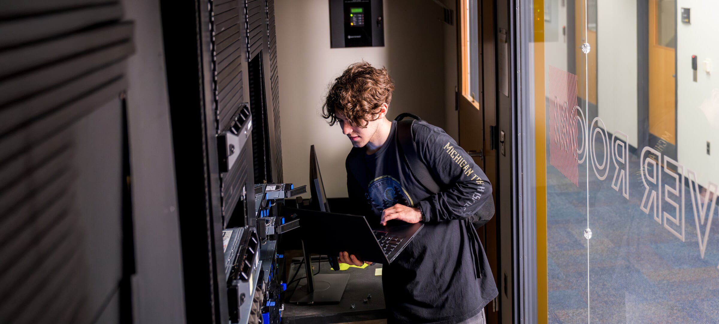 Student with a laptop providing maintenance in a server room