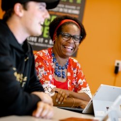 Student and Faculty member sitting at a table laughing