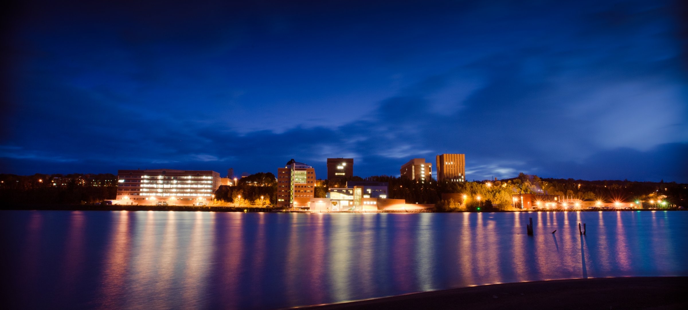 Image of the Michigan Tech campus from the water at night