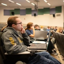 A student sitting in a lecture with a computer