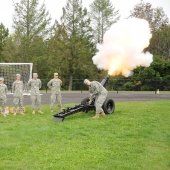 Cadets in formation, one firing the cannon