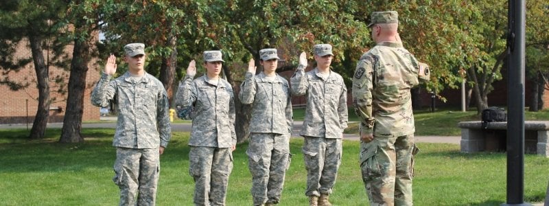 Cadets holding hand up in front of Commander in front of ROTC building