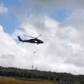 Helicopter with people dropping down on rope.