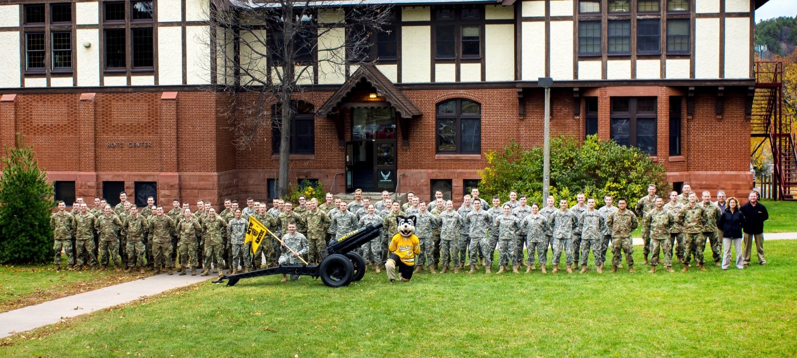 A group image of leadership, students, staff, and Blizzard in formation outside the ROTC building.
