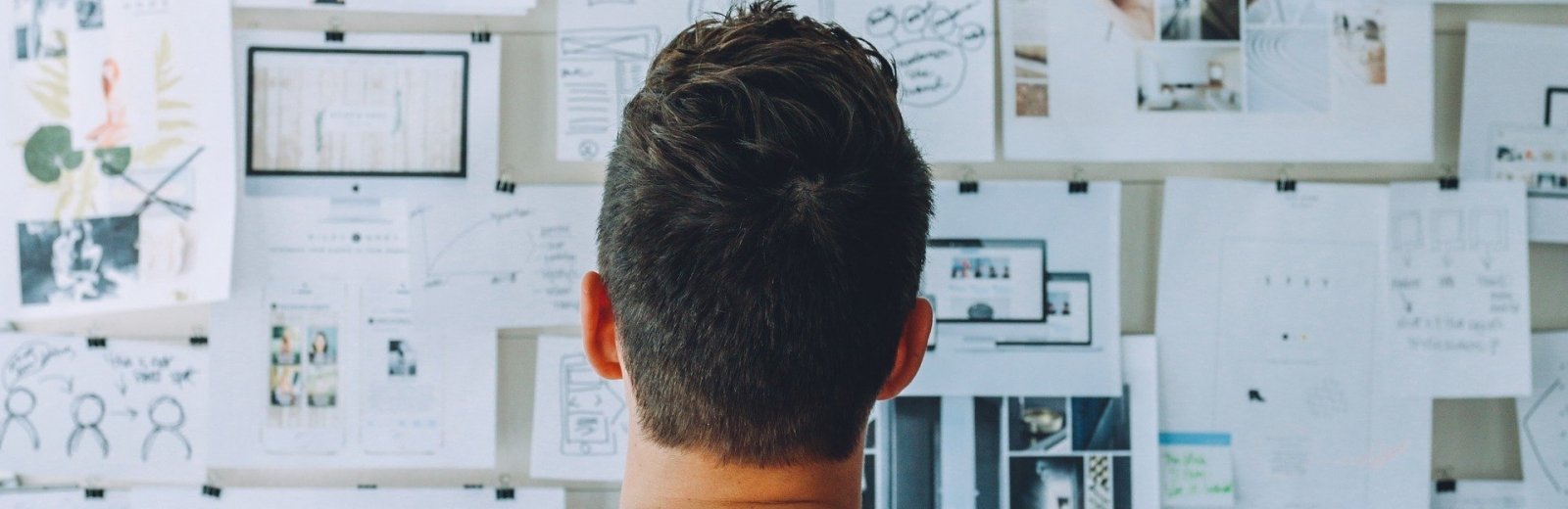 A man looking at a wall of notes. 