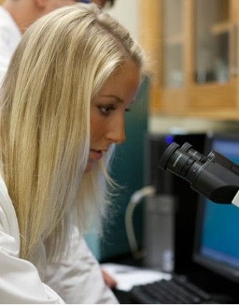 Student looking through a microscope in a Biology Lab