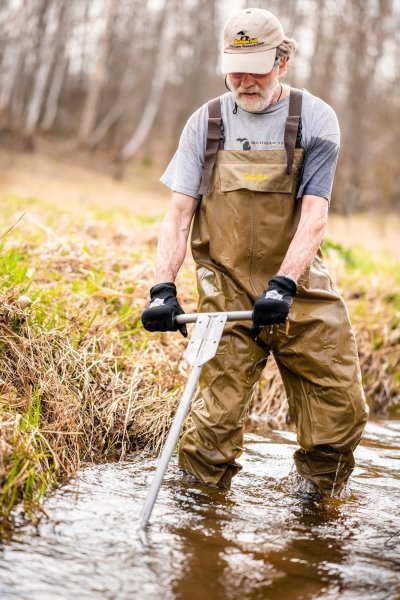 Casey Huckins using a tool in a stream for research