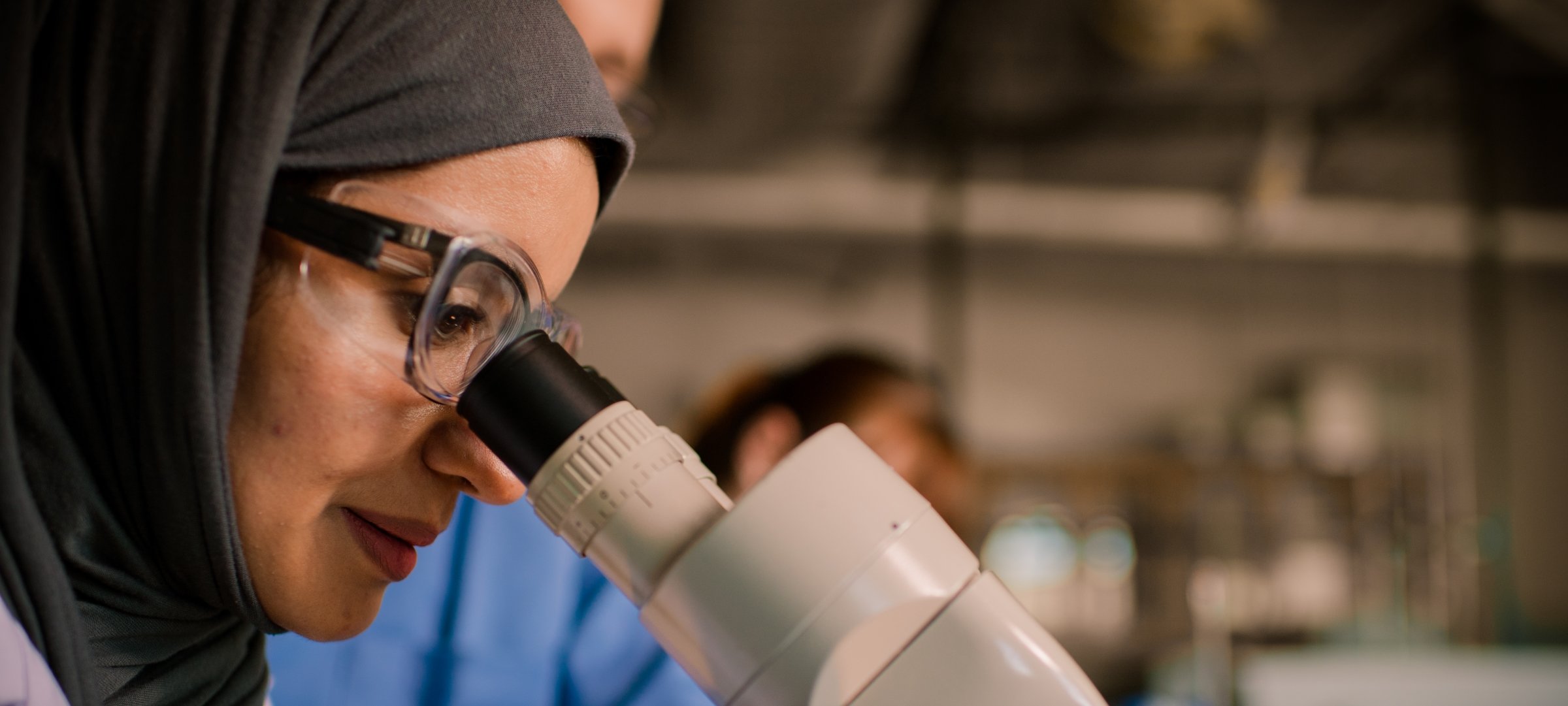 Graduate researcher looking through a microscope.