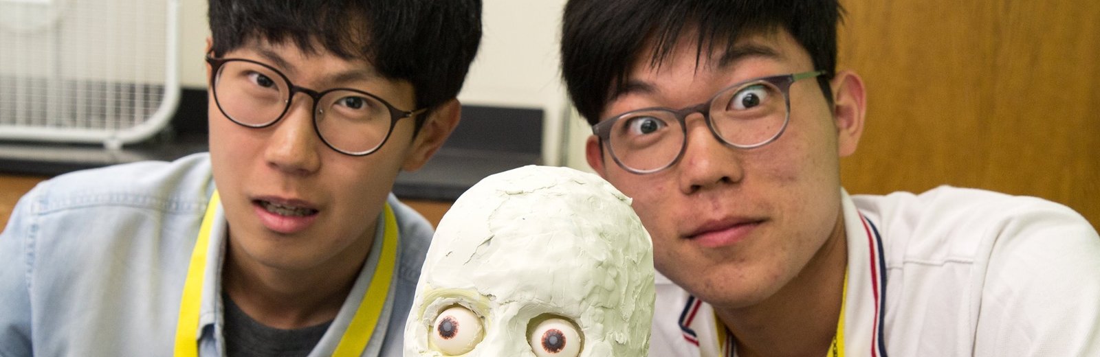 two students pose with a model skull.