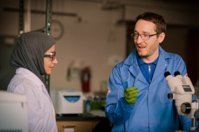 Paul talking to a woman near a microscope