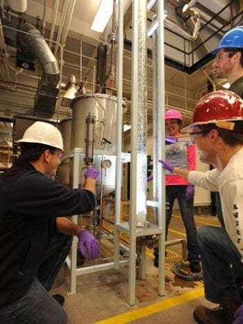 Students work together with hard hats on the floor of a chemical lab