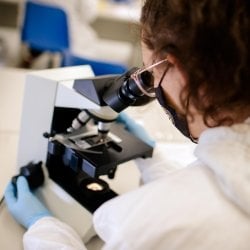 Person looking at a slide in a microscope.