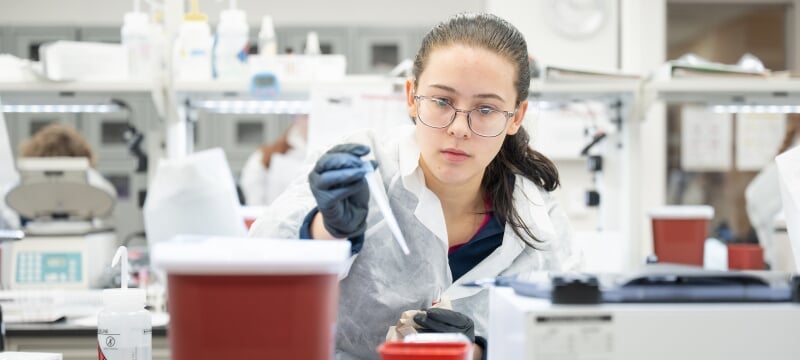 Student in a lab coat working in a medical laboratory science lab.
