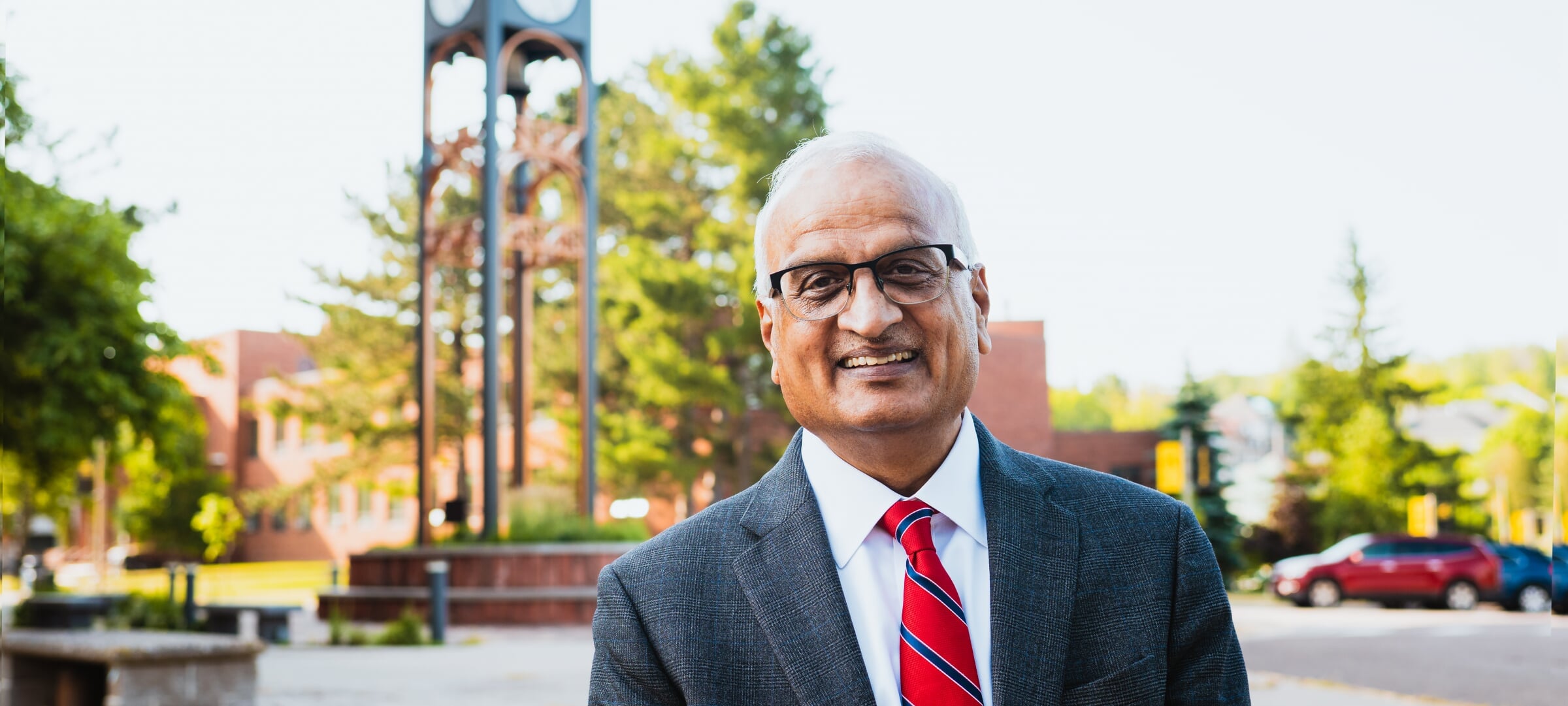 Dean Sri Beldona in front of the clock tower on Michigan Tech's campus.