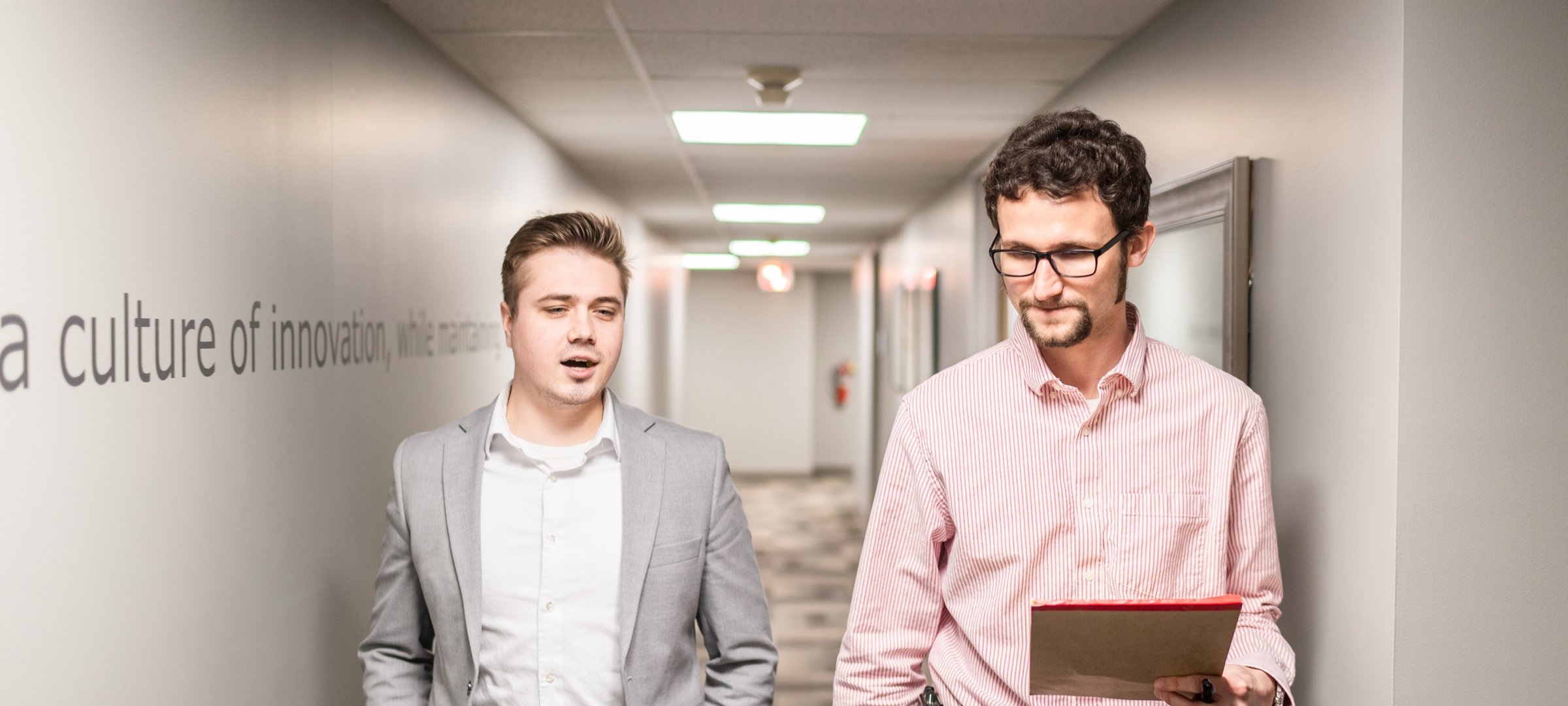 Student walking down a hallway with a professor.