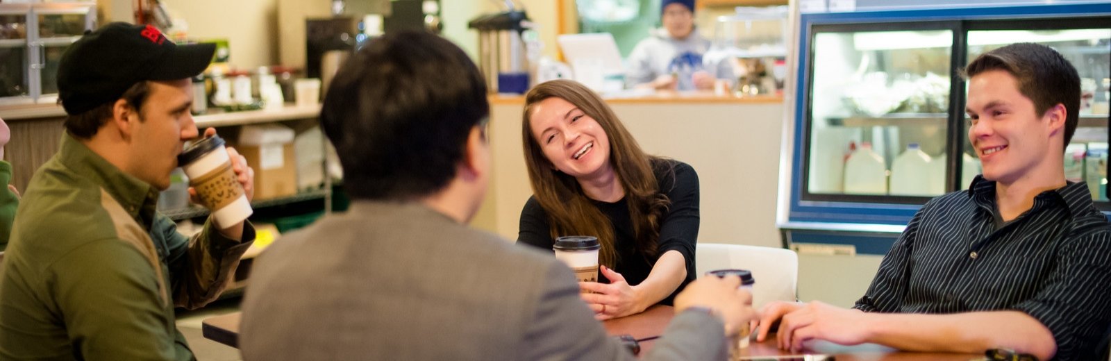 Tanner, Hailey, Thomas, and Dr. Jun Min talking at a table.