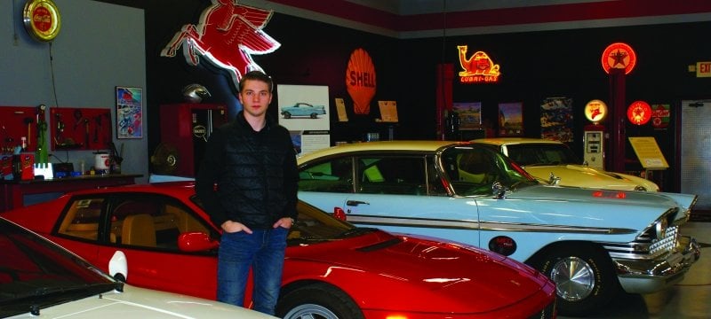 Student standing by fast cars