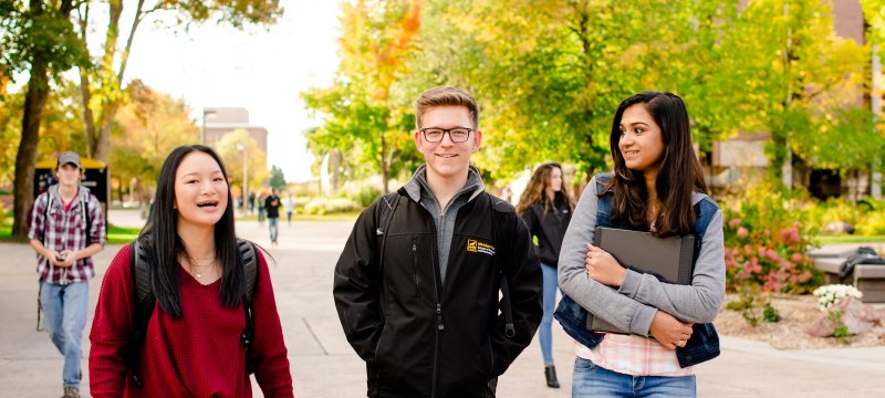 Three students walking on campus.