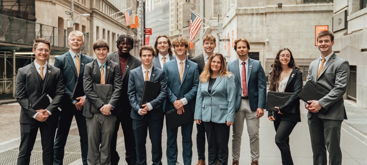 Group of 12 students dressed up and on a street in New York.